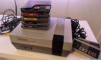 Full view of NES console with controllers, cables, and stacked game cartridges