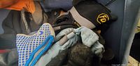 Top view showing several pairs of winter work gloves including black fleece, blue grip gloves, and gray gloves with reinforcements.