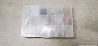 Closed plastic compartment organizer showing contents inside faintly.