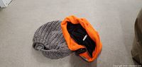 Two winter caps: grey knit beanie and orange fleece cap with snap button