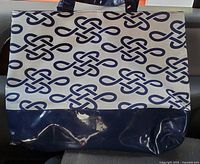 Front view of the tote showing the white canvas material with blue knot pattern and shiny blue vinyl bottom.