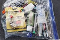 Image showing multiple art supplies such as paint tubes, markers, and packaged buttons inside a clear zip-lock bag