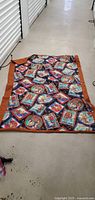 Full view of the blanket laid out showing its overall size, border, and pattern of thematic panels.