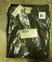 Black ribbed long sleeve top in original plastic packaging with stickers and tags visible