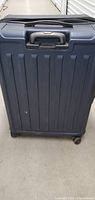 Front view of large hard-shell suitcase in dark blue showing handle and wheel base