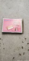 Top view of the closed sewing kit box showing the pink label 'Golden Frame Sewing Kit' with images of the kit contents