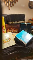 Photo showing a variety of board game boxes including Trivia Challenge, Last Chance, a blue box (likely Hannibal), Monopoly, and others.