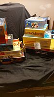 Overall view of the stack of assorted board games including Disney puzzle and Pictionary showing multiple boxed games