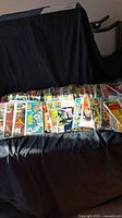 Comic books laid out on black fabric, showing a variety of colorful covers including Marvel titles.