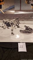 Close-up of unsigned black and white hockey action photo showing players on ice and goalie stretching to block puck