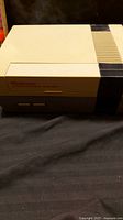Side-angle close-up of one Nintendo Entertainment System console in beige and gray.