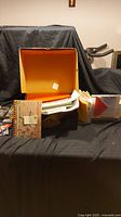 Photo of an open bootbox filled with assorted papers, envelopes, and gift cards including one brightly colored notebook and various stacked papers.