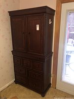 Front view of the wooden armoire showing double cabinet doors and multiple drawers below