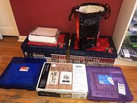 Photo showing 2 decorated Christmas themed advent calendar boxes, one reusable shopping bag, a quilting kit box, and blue plastic containers