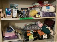 Two shelves filled with crafting supplies showing yarn, buttons in a jar, and pins