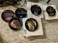Photo showing six NHL hockey team collector plates placed on a floor with some styrofoam packaging. Teams shown: Montreal Canadiens, Toronto Maple Leafs, New York Rangers, Chicago Blackhawks, Detroit Red Wings, Boston Bruins.