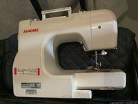 Side view of the white Janome JP 760 sewing machine on carrying case showing general body and handle