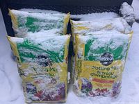 Four bags of Miracle-Gro Potting Mix with snow covering and freezing on the bags.