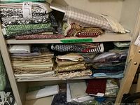 Three shelves of folded fabric pieces and quilt blocks.