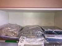Shelf holding multiple quilting kits and fabric batting wrapped in plastic ready for sale.