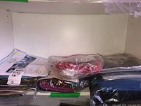 Shelf with multiple bundled fabrics and quilting kits wrapped in plastic.