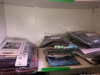 Shelf containing multiple folded quilting kits and fabric packs wrapped in plastic with a visible label