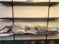 Photo showing multiple quilting kits packaged in clear plastic bags, arranged on a shelf.
