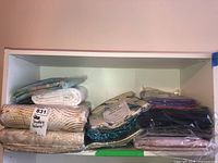 Overview of two shelving levels with multiple unopened quilting fabric packs and backing fabrics.