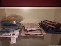 Photo of quilting kits showing multiple stacks of fabric sealed in plastic bags and small finished quilt pieces
