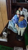 Photo showing two Royal Doulton figurines (Fat Boy and Sweet Anne) positioned on a wooden surface.