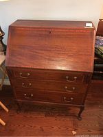 Full view of closed slant front mahogany secretary desk illustrating the inlaid Sheraton line and brass handles.
