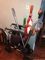 Overview of Evolution Xpresso Lite walker with attached black mesh seat and storage pouch with several canes and one umbrella placed inside or leaned on it.