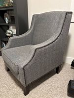 Side angle showing the chair's shape, nailhead trim on the arms, and dark wooden legs.