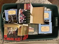 View of a storage bin containing multiple boxes and village pieces, some with attached electrical cords for lighting.