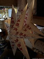 First star lantern showing floral pattern and pointed star shape with dim lighting.