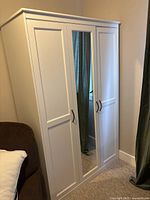 Wardrobe front view showing three doors with center mirror, white with dark handles