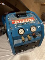 Front view showing Makita Pneumatics sticker, model MAC2400 label, pressure gauges, couplers and regulator knob