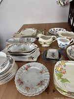 Top view showing collection of various antique and vintage china pieces including plates, gravy boats, and small trays with floral patterns.