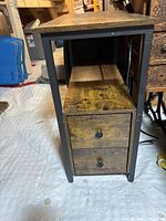 Side view of night stand showing wood drawers with black metal knobs and dark metal frame.