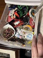 Top view of a drawer showing assorted pins, buttons, colorful nylon lanyards, keychains and badges in mixed condition and packaging.
