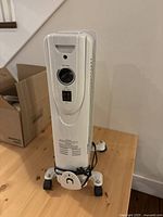 Front view of the electric oil-filled space heater showing the control dial and power switch with the cord wrapped around the base.