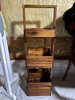 Wooden three-tier storage shelf with three box trays visible from front.