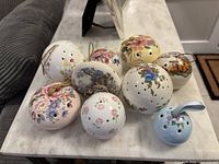 Top view of nine vintage ceramic pomanders with various floral prints, showcasing their size and decoration.