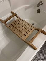 Wood bath caddy resting across an empty standard bathtub, showcasing its size and fit.