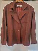 Brown Calvin Klein women's wool blend blazer hanging on a hanger, front view showing button and pockets.