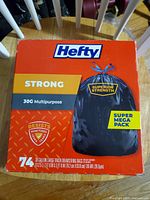 Photo of unopened red box of Hefty 30-gallon multipurpose strong trash bags, 74 count.