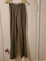 Gray wool dress pants with no pockets hung on a hanger
