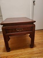 Rectangular wooden end table showing front and side view with decorative legs and drawer