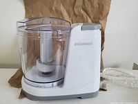 Front view of the assembled food chopper with clear container and Sylvania branding on the white base unit