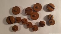 All fourteen chocolate brown buttons arranged on neutral background